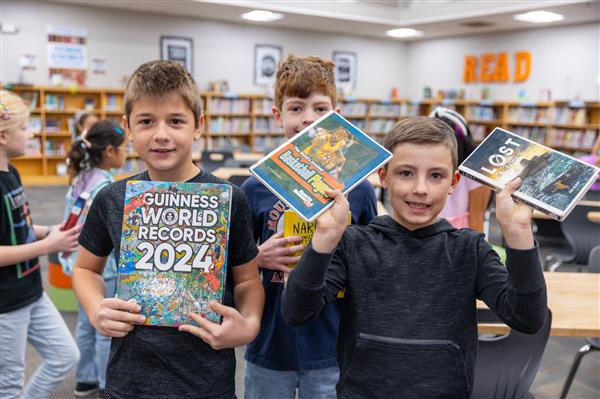 three boys holding books